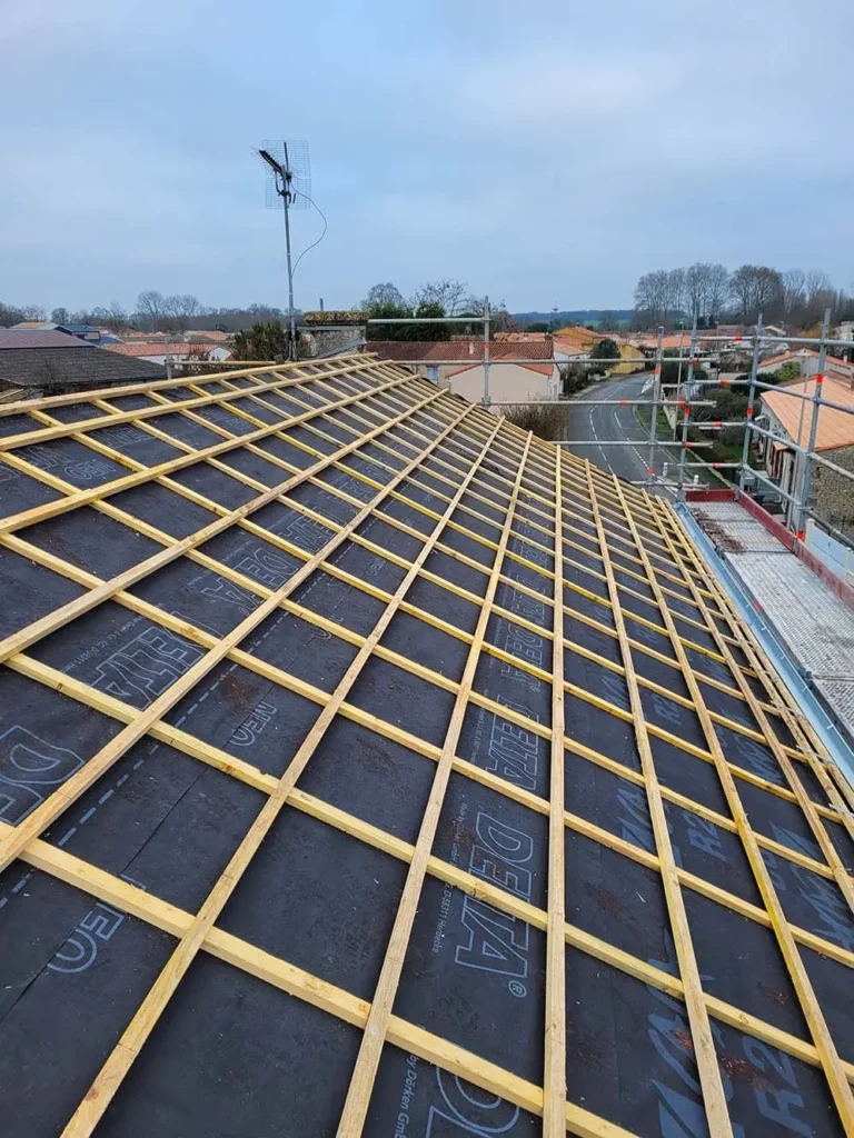 Rénovation de toiture en cours avec la mise en place d'une nouvelle structure en liteaux, améliorant l'isolation et la durabilité.