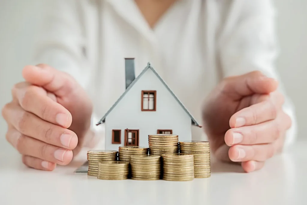Main protégeant une maison miniature avec des pièces, représentant la valorisation immobilière par la rénovation énergétique